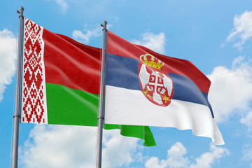 Serbia and Belarus flags waving in the wind against white cloudy blue sky together. Diplomacy concept, international relations.