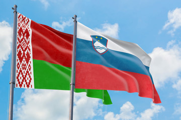 Slovenia and Belarus flags waving in the wind against white cloudy blue sky together. Diplomacy concept, international relations.