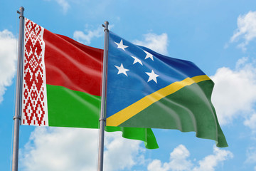 Solomon Islands and Belarus flags waving in the wind against white cloudy blue sky together. Diplomacy concept, international relations.