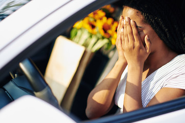Young woman covering face with hands as she is scared after crashing in another car
