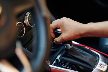 Close-up image of woman smoothly changing gear when driving her new car