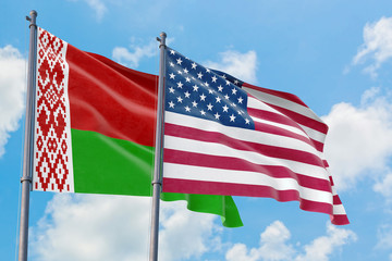Obraz premium United States and Belarus flags waving in the wind against white cloudy blue sky together. Diplomacy concept, international relations.