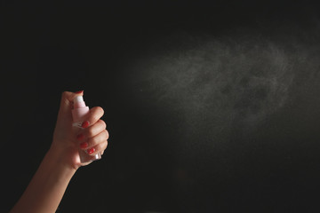 Fototapeta na wymiar Hand using a spray, isolated on black background.