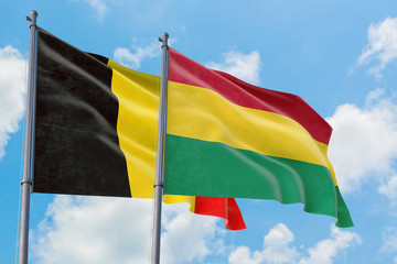 Bolivia and Belgium flags waving in the wind against white cloudy blue sky together. Diplomacy concept, international relations.
