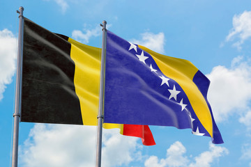 Bosnia Herzegovina and Belgium flags waving in the wind against white cloudy blue sky together. Diplomacy concept, international relations.