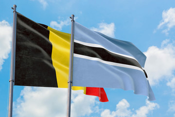 Botswana and Belgium flags waving in the wind against white cloudy blue sky together. Diplomacy concept, international relations.