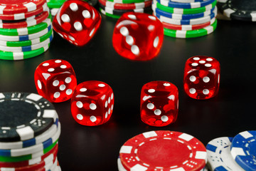Dice and chips on black table close up