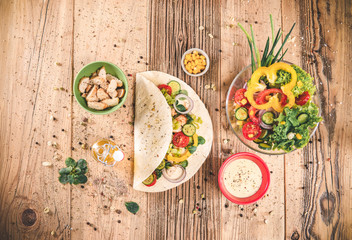 Delicious tortilla wraps on wooden table with vegetable