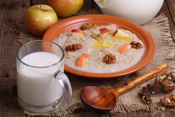 Oatmeal with fruit and milk on a wooden table