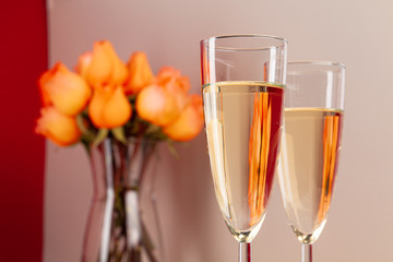 Close up photo of champagne glasses with roses in a vase