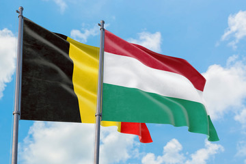 Hungary and Belgium flags waving in the wind against white cloudy blue sky together. Diplomacy concept, international relations.