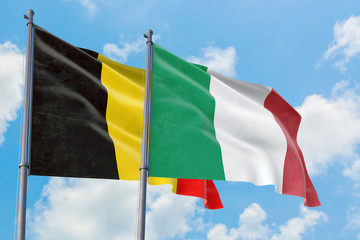 Italy and Belgium flags waving in the wind against white cloudy blue sky together. Diplomacy concept, international relations.