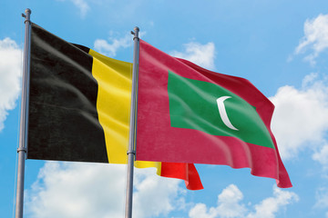 Maldives and Belgium flags waving in the wind against white cloudy blue sky together. Diplomacy concept, international relations.