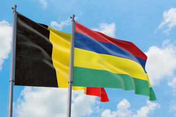 Mauritius and Belgium flags waving in the wind against white cloudy blue sky together. Diplomacy concept, international relations.