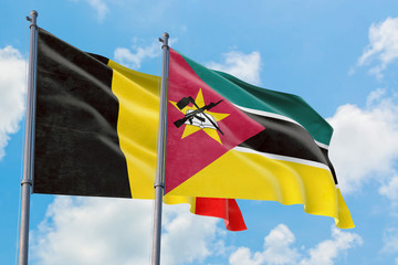 Mozambique and Belgium flags waving in the wind against white cloudy blue sky together. Diplomacy concept, international relations.