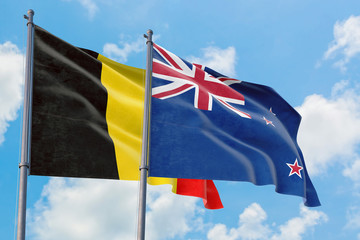 New Zealand and Belgium flags waving in the wind against white cloudy blue sky together. Diplomacy concept, international relations.