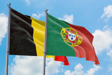 Portugal and Belgium flags waving in the wind against white cloudy blue sky together. Diplomacy concept, international relations.