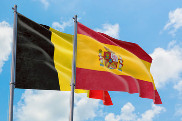 Spain and Belgium flags waving in the wind against white cloudy blue sky together. Diplomacy concept, international relations.
