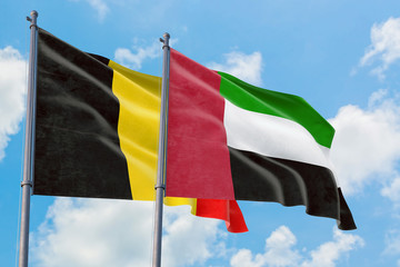 United Arab Emirates and Belgium flags waving in the wind against white cloudy blue sky together. Diplomacy concept, international relations.
