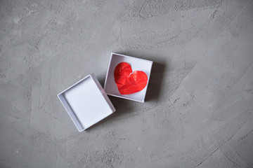 crumpled paper heart in gift box on the concrete floor.  Broken relationships in bad Valentine's day. concept.