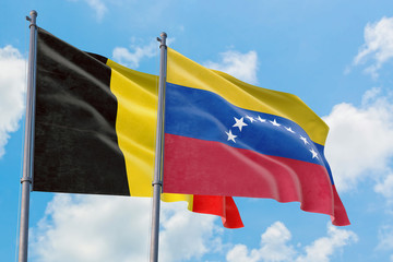 Venezuela and Belgium flags waving in the wind against white cloudy blue sky together. Diplomacy...