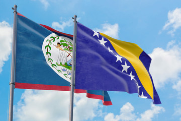 Bosnia Herzegovina and Belize flags waving in the wind against white cloudy blue sky together....