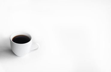 White cup of coffee on a white table with place for text. Top view.