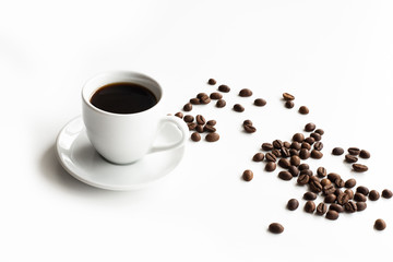 White cup of coffee and saucer on a white table scattered coffee grains with place for text top view