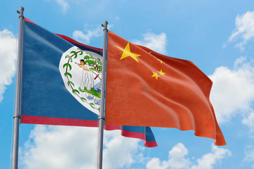 China and Belize flags waving in the wind against white cloudy blue sky together. Diplomacy concept, international relations.