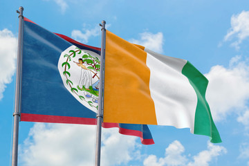 Cote D'Ivoire and Belize flags waving in the wind against white cloudy blue sky together. Diplomacy concept, international relations.
