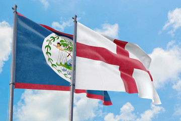 England and Belize flags waving in the wind against white cloudy blue sky together. Diplomacy...
