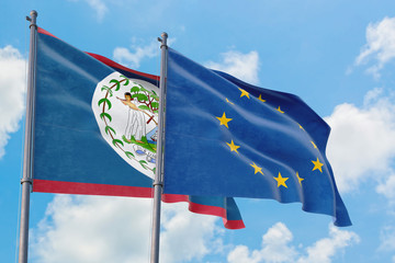 European Union and Belize flags waving in the wind against white cloudy blue sky together....