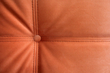 Detail of a classic sofa. The orange sofa. Button in the upholstery of the sofa. Grunge background.