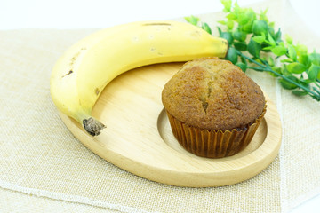 Top view of well baked delicious banana cupcake with banana on brown tablecloth and green plant, isolated on white background. For food photography, party, decoration, delicious, yummy theme