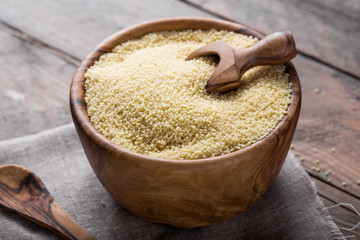 Couscous grain in wooden bowl. Selective focus