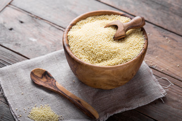 Raw Couscous in a wooden bowl on the table