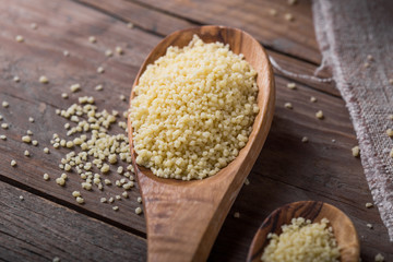 Raw Couscous in a wooden bowl on the table