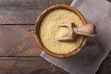 Raw Couscous in a wooden bowl on the table