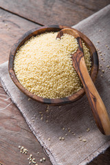 Raw Couscous in a wooden bowl on the table