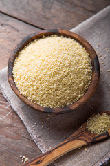 Raw Couscous in a wooden bowl on the table