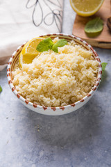 Couscous with mint and lemon in plate on dark rustic table from above. Copy space for text. Flat lay.