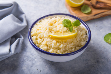 Couscous with mint and lemon in plate on dark rustic table from above. Copy space for text. Flat lay.