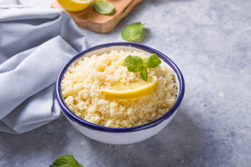 Couscous with mint and lemon in plate on dark rustic table from above. Copy space for text. Flat lay.