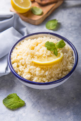 Couscous with mint and lemon in plate on dark rustic table from above. Copy space for text. Flat lay.