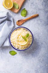 Couscous with mint and lemon in plate on dark rustic table from above. Copy space for text. Flat lay.
