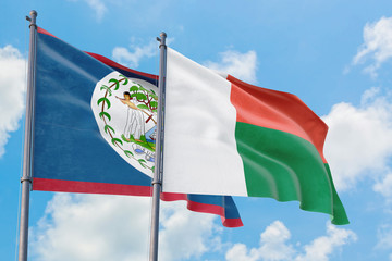 Madagascar and Belize flags waving in the wind against white cloudy blue sky together. Diplomacy concept, international relations.