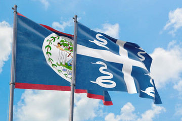 Martinique and Belize flags waving in the wind against white cloudy blue sky together. Diplomacy...