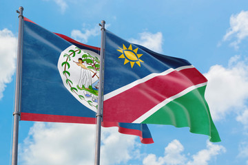 Namibia and Belize flags waving in the wind against white cloudy blue sky together. Diplomacy concept, international relations.