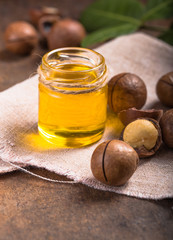 Ripe macadamia nuts and a glass bottle with natural oil Source of natural vitamins and minerals. Selective focus.
