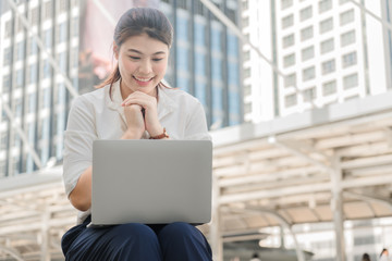 Asian businesswoman is sitting happily and successfully working with a laptop.